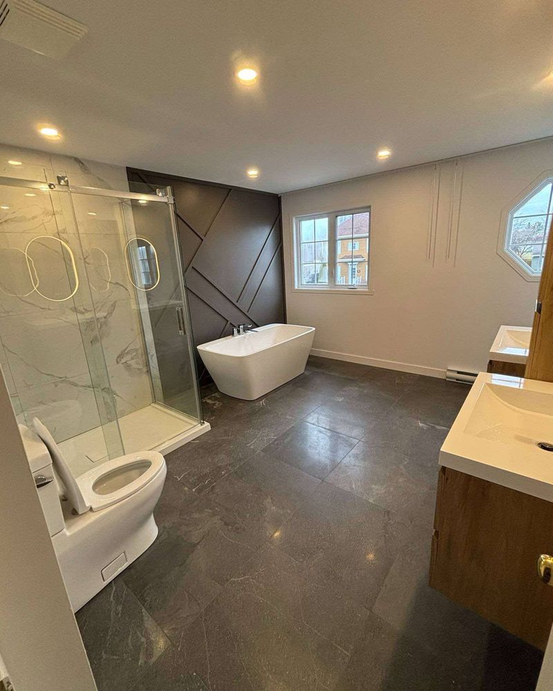 Finished bathroom with glass shower and freestanding tub.