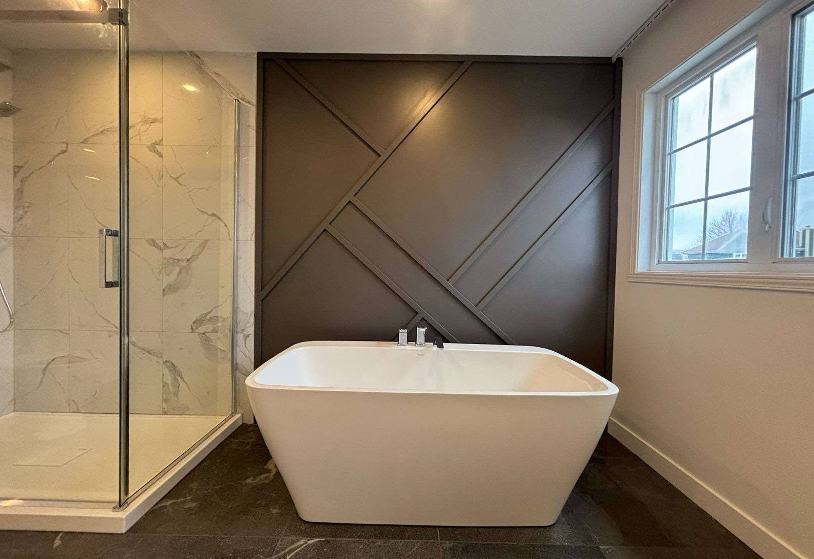 Finished bathroom: glass shower, freestanding tub, dark accent wall.